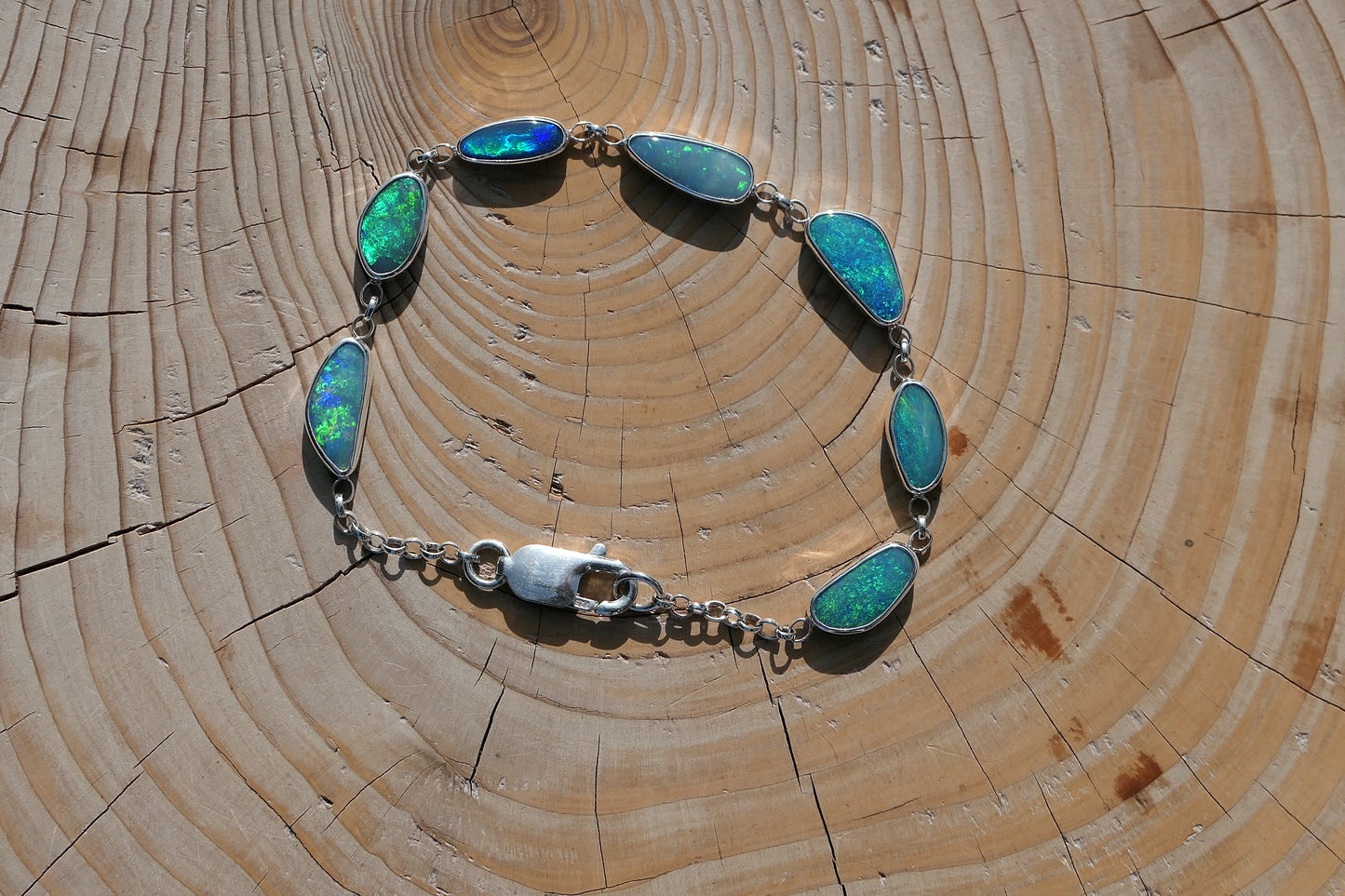 Beautiful opal bracelet in silver. Opals are very bright greens, blue and purple and vary from 15x7 to 11x5mm in size. Length is 200mm 8" with a crocodile catch.