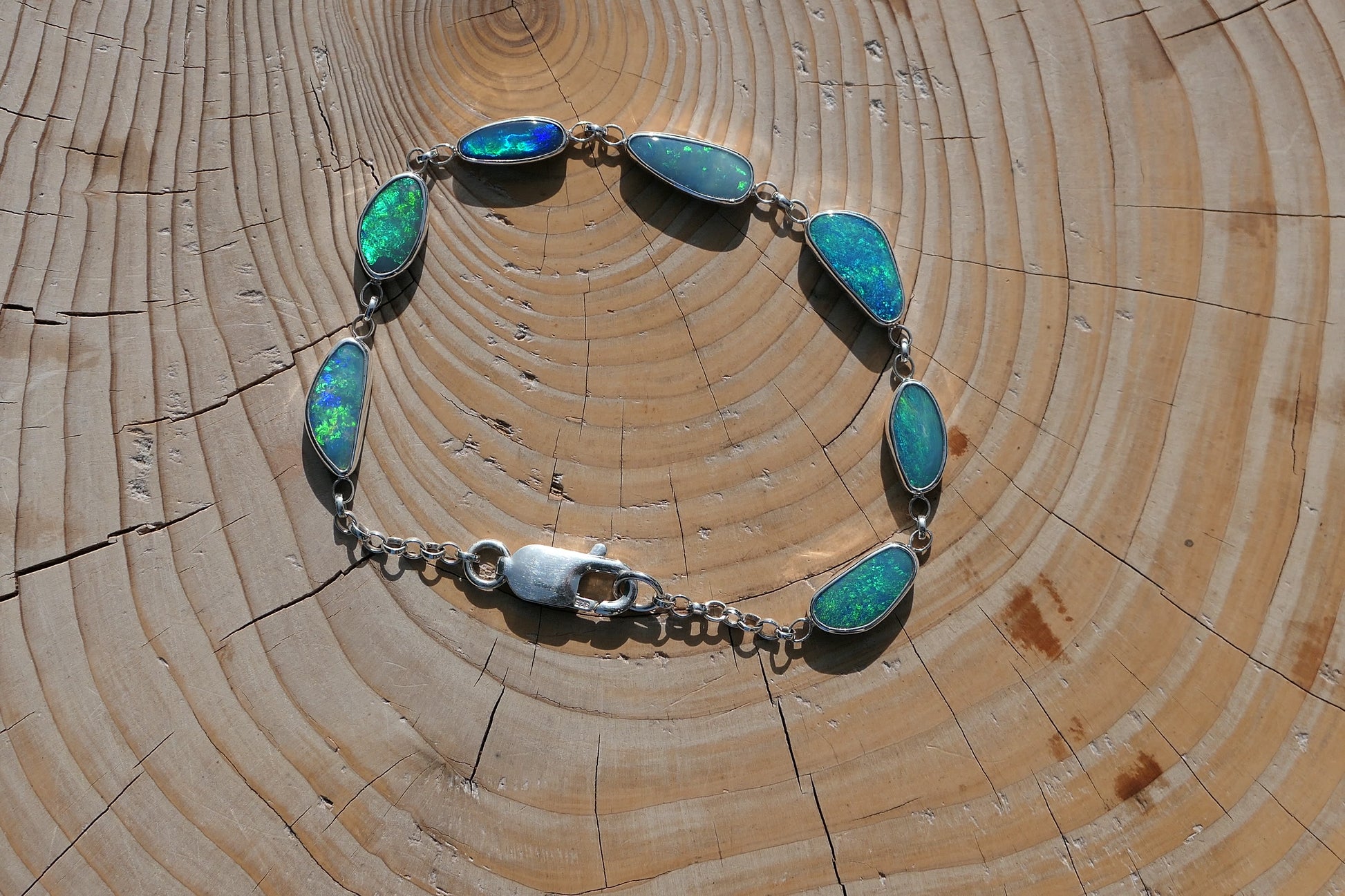 Beautiful opal bracelet in silver.  Opals are very bright greens, blue and purple and vary from 15x7 to 11x5mm in size.  Length is 200mm 8" with a crocodile catch.