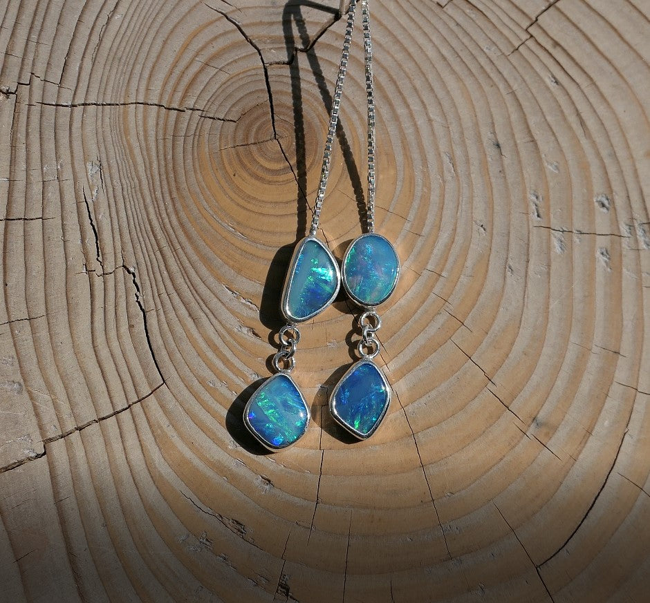 Beautiful dangle and drop  opal earrings made in silver.  Earrings feature four Lightning Ridge opals  on a 40mm drop chain, the opals are green and blues and have bright colours from all angles.  Overall length of earrings is 70mm